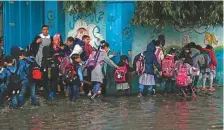  ?? AFP ?? Schoolchil­dren walk in a flooded street during heavy rain in Gaza City yesterday. Normal life was badly disrupted.