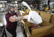  ?? CHARLES REX ARBOGAST/AP ?? Volunteer Linda Nordin places a meat package into a box with other food at the Northern Illinois Food Bank. The food will be delivered by DoorDash drivers to homebound clients.