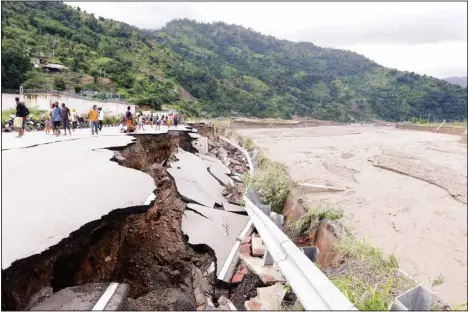  ?? (AP) ?? Residents inspect a damaged road following a flood in Dili, East Timor, Monday, April 5. Multiple disasters caused by torrential rains in eastern Indonesia and neighborin­g East Timor have left a number of people dead or missing as rescuers were hampered by damaged bridges and roads and a lack of heavy equipment Monday.