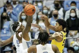  ?? GERRY BROOME — THE ASSOCIATED PRESS ?? Michigan guard Eli Brooks (55) passes while North Carolina forward Armando Bacot (5) and guard Caleb Love defend during the game in Chapel Hill, N.C., Wednesday.