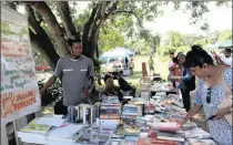 ?? PICTURE: ARUSHAN NAIDOO ?? Nkosingiph­ile Ndlovu manning his stall under the mahogany tree with keen bookworm Jurie Thaver.