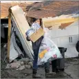  ?? The Associated Press ?? Mario Mendoza carries items out of a friend’s storm-damaged home Tuesday.