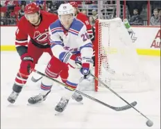  ?? Chris Seward / Associated Press ?? The Carolina Hurricanes’ Jaccob Slavin, left, and New York Rangers’ Jimmy Vesey, right, vie for the puck during the first period Tuesday in Raleigh, N.C. The Rangers won 2-1.