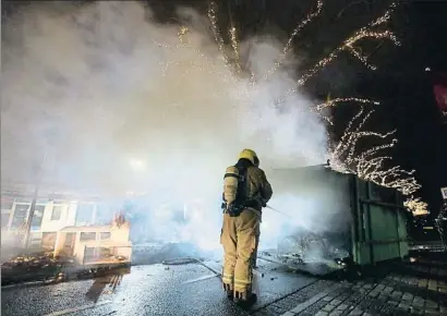  ?? PETER DEJONG / AP ?? Un bombero de Rotterdam apagando un container ardiendo la noche del lunes
