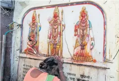  ??  ?? PAYING HOMAGE: A Hindu pilgrim touches in obeisance images of Hindu deities Rama, Sita and Lakshman in Ayodhya, India yesterday.