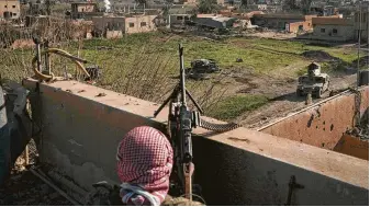  ?? Felipe Dana / Associated Press ?? A U.S.-backed Syrian Democratic Forces fighter peers out Monday at the remaining land still held by Islamic State militants in Baghouz, Syria. They are preparing for a final assault there.