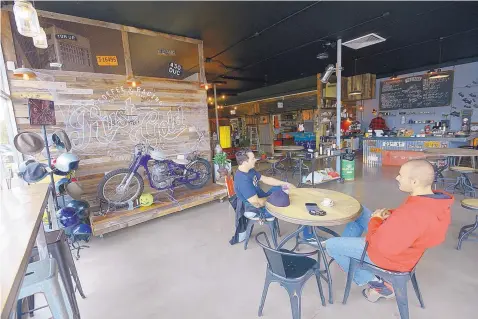  ?? ADOLPHE PIERRE-LOUIS/JOURNAL ?? Eric Wong, left, and Mike Hernandez take a break at Rust is Gold Coffee, a vintage motorcycle-inspired space within The ABQ Collective.