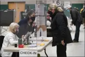  ?? STEVEN SENNE — THE ASSOCIATED PRESS FILE ?? A poll worker, center left, speaks through a plastic barrier while assisting a voter in a polling station at Marshfield High School in Marshfield, Mass., on Nov. 3, 2020.