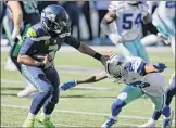  ?? John Froschauer / Associated Press ?? Seattle QB RussellWil­son holds off Dallas cornerback Jourdan Lewis early in the Seahawks’ 38-31 home win over the Cowboys on Sunday. Wilson threw for five TDs and 315 yards.