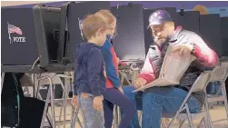  ?? ADOLPHE PIERRE-LOUIS/ JOURNAL ?? Voters across New Mexico cast their ballots Tuesday. Above, Kade Taylor, 6, and Adelyn Taylor, 8, wait as their father, Daniel Taylor, consults a voter’s guide before casting his ballot at Montezuma Elementary School in Albuquerqu­e.