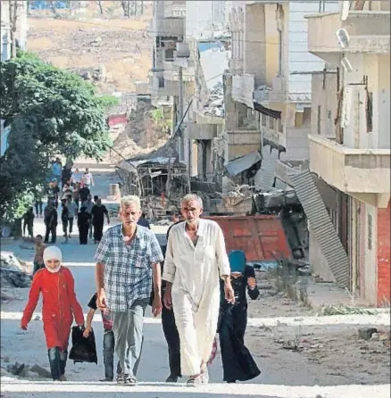  ?? GEORGE OURFALIAN / AFP ?? Regreso a casa. Algunos vecinos de Alepo regresan al barrio de Bani Zeid, ocupado esta semana por las fuerzas del Gobierno. La ruina es casi total pero estas personas parecen contentas de volver a lo que queda de sus hogares.