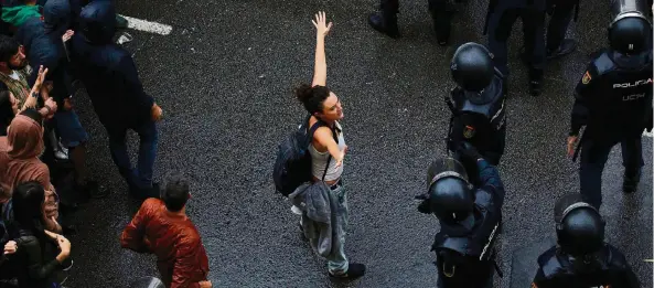  ?? FOTO: DPA ?? Eine junge Frau stellt sich zwischen Befürworte­r des Referendum­s und die Polizei. Die Beamten sollen verhindern, dass die Wähler ihre Stimme in einer Schule abgeben.