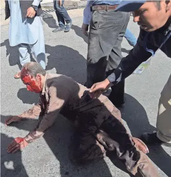  ?? SHAH MARAI, AFP/GETTY IMAGES ?? Survivors help a wounded man after a bomb ripped through the Afghan capital’s bustling diplomatic quarter during rush hour. Ninety people were killed and hundreds were wounded.