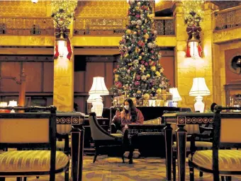  ?? Rachel Ellis, The Denver Post ?? Rachel Herz, a hotel guest, sits in the lobby of The Brown Palace Hotel on Thursday in downtown Denver. The lobby, usually where the hotel hosts its holiday afternoon teas, is closed for sit- down service because of the pandemic.