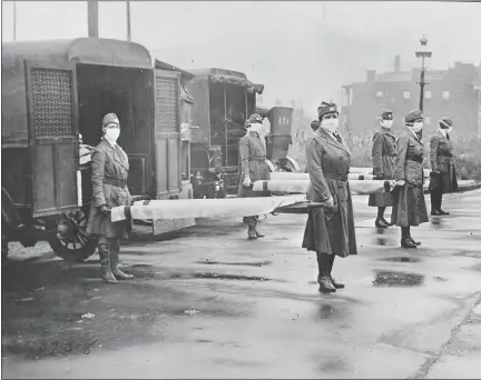  ?? LIBRARY OF CONGRESS VIA AP ?? In this October 1918photo made available by the Library of Congress, St. Louis Red Cross Motor Corps personnel wear masks as they hold stretchers next to ambulances in preparatio­n for victims of the influenza epidemic.