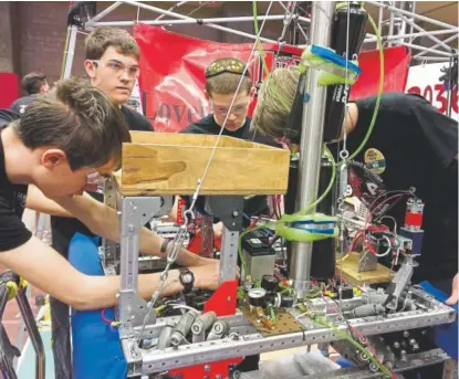  ?? Amanda Trejos, The Denver Post ?? Members of The Power Squids, a team from Loveland High School, work on their robot before having it compete in the FIRST Robotics’ Colorado regional in Magness Arena at the University of Denver on Friday.