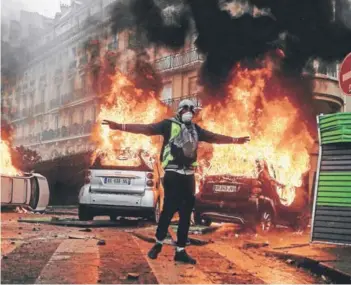  ??  ?? ► Un manifestan­te cerca de un automóvil en llamas ayer, en la protesta en París.
