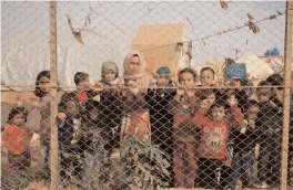  ?? — AFP ?? Displaced Syrian children stand behind a fence outside their tents a camp set up near the village of Kafr Lusin, near the Syria-Turkey border.
