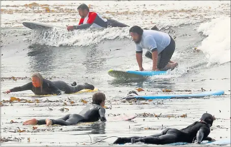  ?? SHMUEL THALER — SANTA CRUZ SENTINEL ?? U.S. Marine Corps veteran William Condon gets in position to stand on his board as he surfs at Monday’s Veteran Surf Alliance event at Capitola Beach.