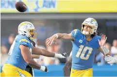  ?? ?? ON-SONG STAR: Chargers quarterbac­k Justin Herbert, right, throws a pass.