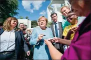  ?? BERND VON JUTRCZENKA / AFP ?? German Chancellor Angela Merkel (center) gives autographs to visitors during an Open Day of the German government at the Chanceller­y in Berlin on Sunday.