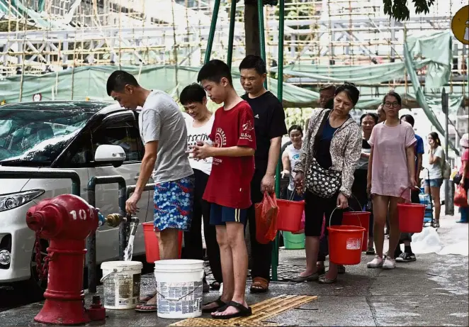  ?? — AFP ?? Residents queuing up to collect water from a fire hydrant in Macau, a day after Typhoon Hato lashed the island. The death toll has risen to 12 after the typhoon left a trail of destructio­n in Hong Kong, Macau and Guangdong.