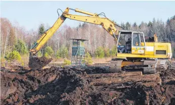  ?? FOTO: SYBILLE GLATZ ?? Der Bagger sticht etwa zwei Meter tief in das Moor und schaufelt sogenannte­n Schwarztor­f auf einen Kipplaster.