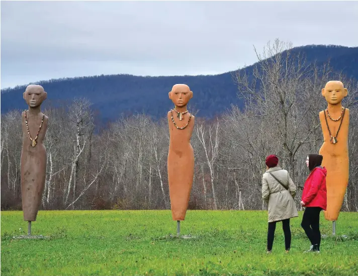 ?? ?? Dressed up for the cold, a couple of people walk to see the 12 sculptures in Rose B. Simpson’s public art installati­on, “Countercul­ture”, on view from Sloan Road at Field Farm in Williamsto­wn, Massachuse­tts, on Sunday, Photo: Gillian Jones/The Berkshire Eagle via AP