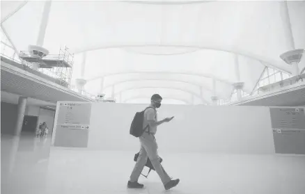  ?? DAVID ZALUBOWSKI/AP ?? A traveler passes a constructi­on zone July 2 on the way to the gates at Denver Internatio­nal Airport.