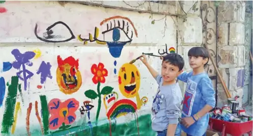  ??  ?? Om’s sons Zane and Wissam paint a mural in East Aleppo