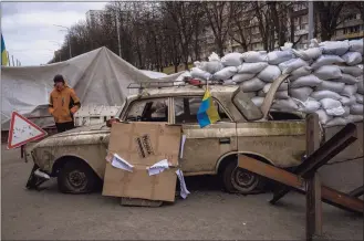  ?? Emilio Morenatti / Associated Press ?? A militia man stands at a checkpoint set up on a road heading to the city of Kyiv, Ukraine, Saturday. Russian troops took control of the southern port city of Kherson last week. Although they have encircled Kharkiv, Mykolaiv, Chernihiv and Sumy, Ukrainian forces have managed to keep control of key cities in central and southeaste­rn Ukraine, Ukrainian President Volodymyr Zelenskyy said Saturday.