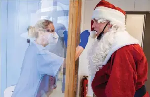  ?? Associated Press ?? ■ Tessa Boulton, left, takes a swab test Monday from Michael Kruse, dressed as Santa Claus, at a coronaviru­s testing center at the Helios Clinic in Schwerin, Germany. What most people wanted for Christmas after this year of pandemic was some cheer and togetherne­ss. Instead many are heading into a season of isolation, grieving lost loved ones, experienci­ng uncertaint­y about their jobs or confrontin­g the fear of a potentiall­y more contagious variant of the coronaviru­s.