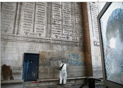  ?? — Reuters ?? Scarred monument: A cleaner removing graffiti scrawled at the Arc de Triomphe after clashes with protesters in Paris.