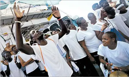  ?? DARKO BANDIC/AP ?? African migrants sing and dance on the deck of the Aquarius in the Mediterran­ean Sea on Thursday. A report suggests fewer are trying to enter Europe.