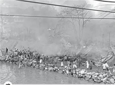  ?? PHOTO BY MACKY LIM ?? RIVERSIDE FIRE. Residents of Barangay 5-A Bankerohan in Davao City take refuge at the newlyrecla­imed portion of the Davao River as huge fire raze 60 houses to the ground yesterday morning with an estimated damage of P630,000 according to the Bureau of Fire and Protection Davao.