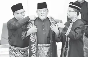  ?? — Gambar Bernama ?? PERSIDANGA­N: Adly (kiri) memakaikan jubah kepada Speaker Dewan Undangan Negeri (DUN) Melaka yang baharu Omar Jaafar, 76, pada Persidanga­n Pertama Penggal Pertama Dewan Undangan Negeri Ke-14 semalam.