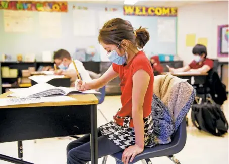  ?? STACEY WESCOTT / CHICAGO TRIBUNE PHOTOS ?? Fifth grader Evelyn Duran works on a writing assignment at O’Neal Elementary School in Elgin on Friday. The district superinten­dent is among hundreds in Illinois who want standardiz­ed testing waived this spring.