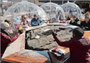  ??  ?? A group of friends sits around a fire pit social distancing while other customers relax in plastic domes at the Jealous Monk social hall & beer garden.