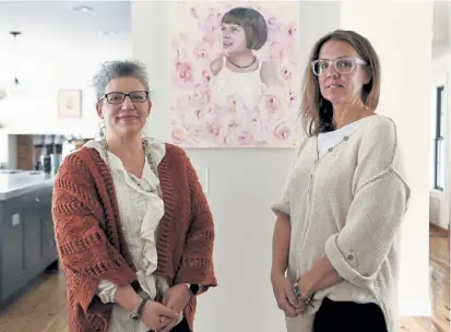  ?? Andy Cross, The Denver Post ?? Realm of Caring founders Heather Jackson, left, and Paige Figi, mother of the late Charlotte Figi, stand in Paige’s house Thursday in Colorado Springs with a painting of Charlotte behind them by artist Nichole Montanez.