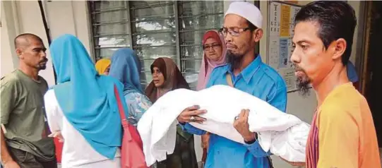  ?? [FOTO NAZIRUL ROSELAN/BH] ?? Muhammad Rizal memangku jenazah anaknya keluar dari bilik forensik Hospital Jengka, semalam.