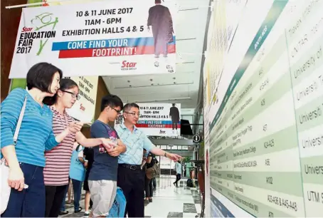  ??  ?? (From left) Yap Teen Teen taking a look at the Star Education Fair 2017 directory outside the halls with her children Xiu Ru and Jun Kai and husband Chung Boon Ann.