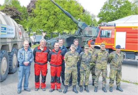  ?? FOTO: SUSANNE GRIMM ?? Zum Fototermin stellen sich Mitarbeite­r und Besatzung des Sanitätsdi­enstes, der Feuerwehr, der Kampfmitte­lbeseitige­r und des Artillerie­bataillons auf. Im Hintergrun­d ist der gepanzerte Notarztwag­en „Boxer“zu sehen sowie die Panzerhaub­itze 2000 und ein...