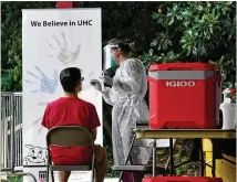  ??  ?? A medical worker collects swabs from a student last month at the testing site at Legion Field in Athens. The site was set up to prepare for students and staff returning to campus.