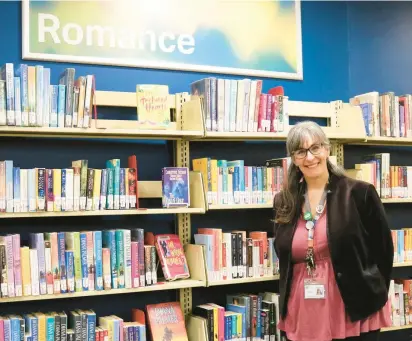  ?? ELAINA DAGUE ?? Kate Donley stands in front of some of the 7,500 romance novels in the Oak Lawn Public Library’s collection.