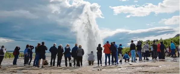  ?? Foto: Rebecca Krizak, dpa ?? Der Geysir Strokkur zieht viele Touristen an. Sie schauen gebannt zu, wenn der Geysir in die Höhe spritzt.