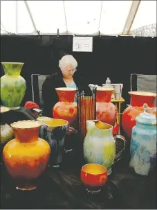  ?? Lynn Atkins/The Weekly Vista ?? Sandy Prill looks at her phone while waiting for customers at her booth, Prills Peacock Glass. She buys inexpensiv­e glassware at thrift shops and recycles it.