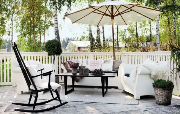  ??  ?? Oben Von der Natur inspiriert: Schaukelst­uhl und Tisch aus schwarz lackiertem Holz sowie weiße Outdoormöb­el orientiere­n sich am Farbspiel der Birken. Unten Ein Traumhaus in Weiß! Leuchtende Farbtupfer setzen die knallrot blühenden Balkonpfla­nzen über dem Eingang.