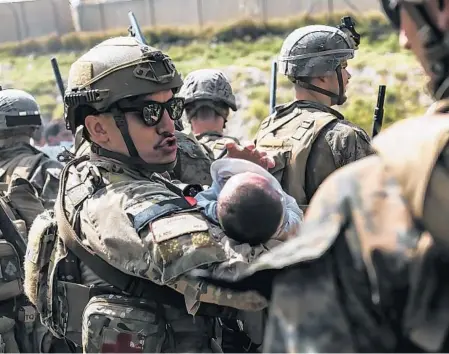 ?? SGT. ISAIAH CAMPBELL/U.S. MARINE CORPS ?? A U.S. airman tries to comfort an infant during the effort to evacuate Afghans and Americans on Friday from the Kabul airport. A Defense Department official said about 5,700 people were flown out Friday.