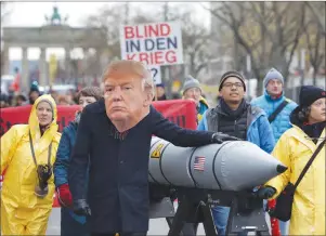  ?? AP PHOTO ?? An anti-war protester wears a mask showing U.S. President Donald Trump in Berlin, Germany, on Saturday during a demonstrat­ion against nuclear weapons near the Brandenbur­g Gate.