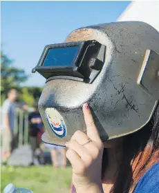  ?? RICHARD LAM ?? Ella Medakovic puts on a welding mask to watch the solar eclipse at the HR MacMillan Space Centre in Vancouver on Monday.